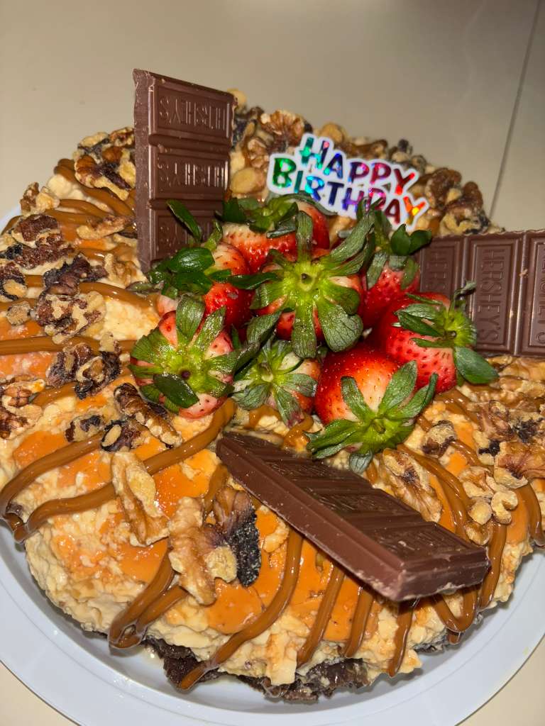 Birthday chocoflan topped with dulce de leche, chocolate, pecans, and strawberries