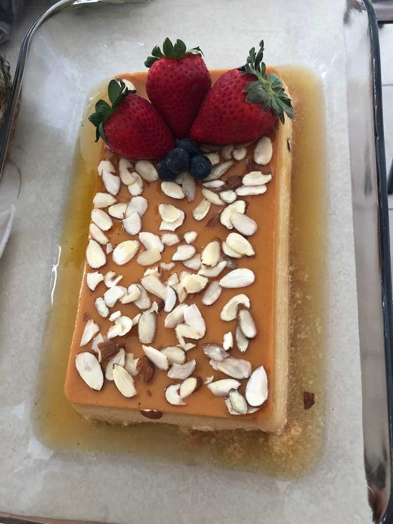 Rectangular caramel flan topped with almonds and fresh berries